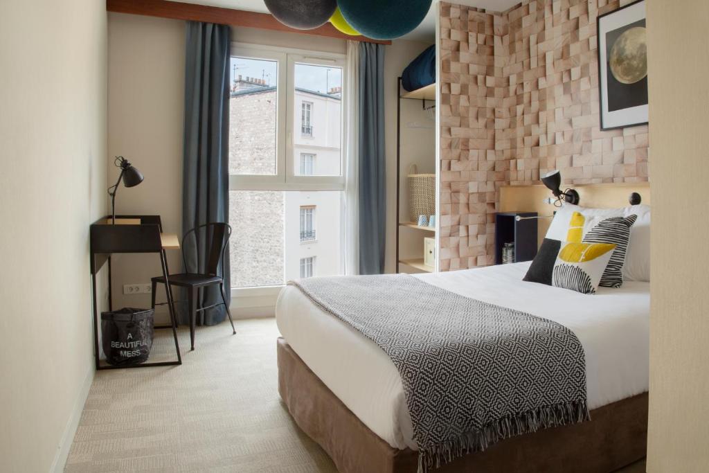 - une chambre avec un grand lit et un mur en briques dans l'établissement Hotel Bootcamp, à Issy-les-Moulineaux