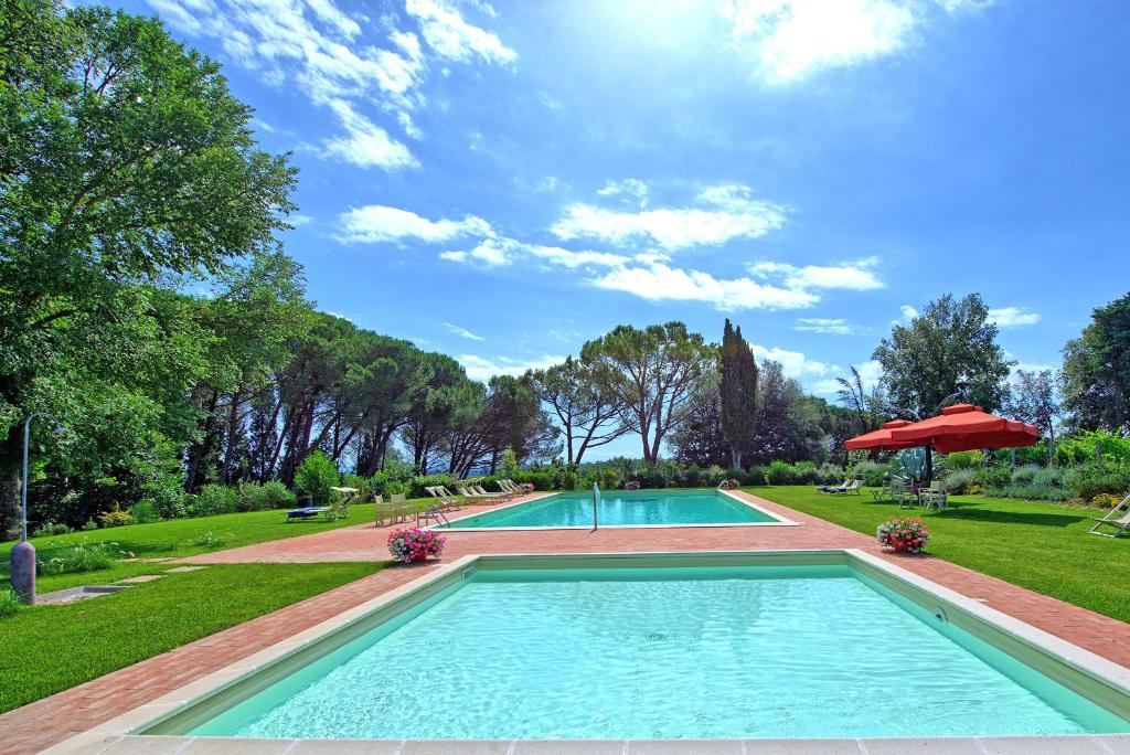 een zwembad in een park met een rode paraplu bij Villa Lorenza by PosarelliVillas in Bucciano