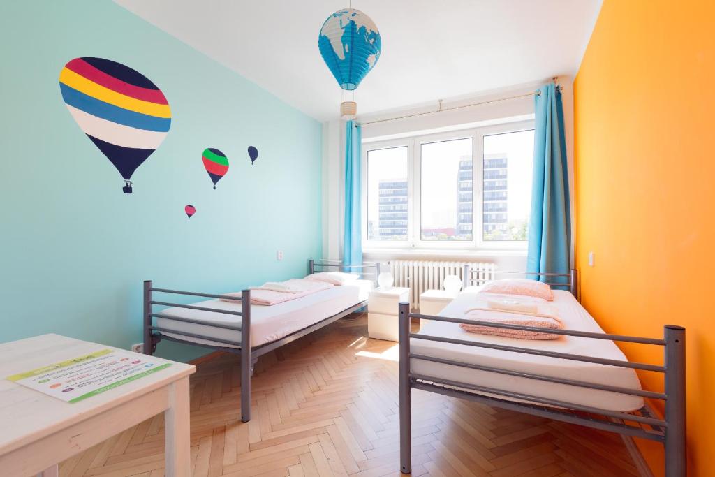 a room with two beds and a table and a window at Patio Hostel in Bratislava