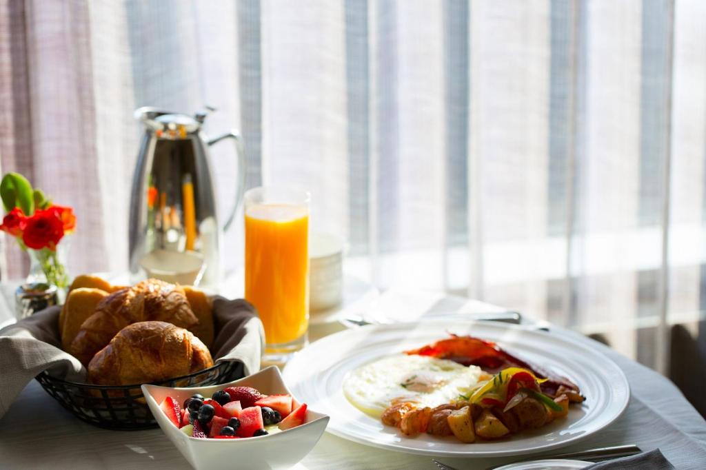 un tavolo con un piatto di cibo e un bicchiere di succo d'arancia di Fraser Suites Muscat a Mascate