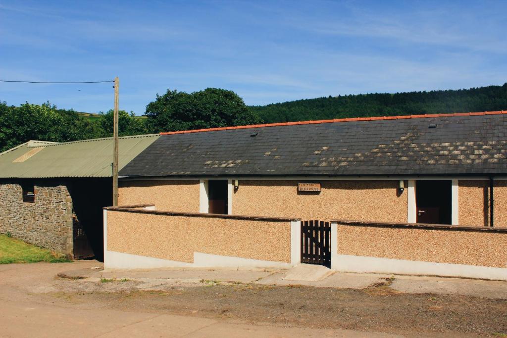 an old brick building with a black roof at Taff Trail Bunkhouse in Merthyr Tydfil