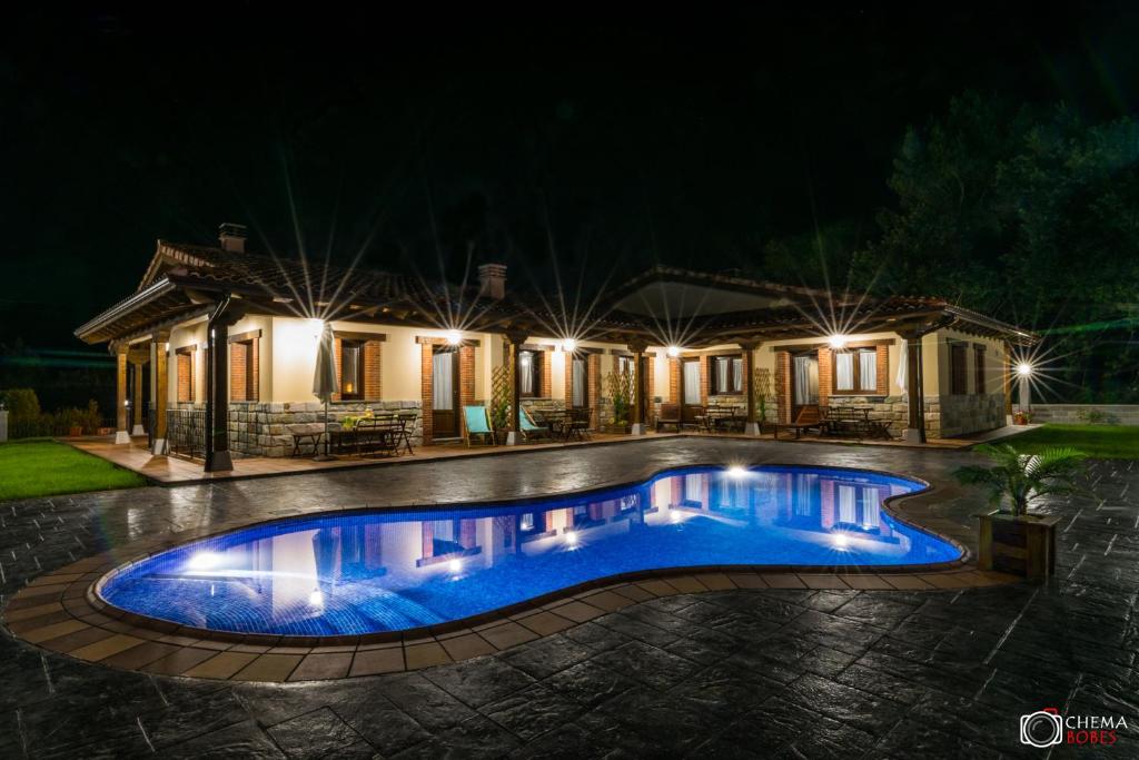 a swimming pool in front of a house at night at Las Carriles Apartamentos rurales in Oviñana