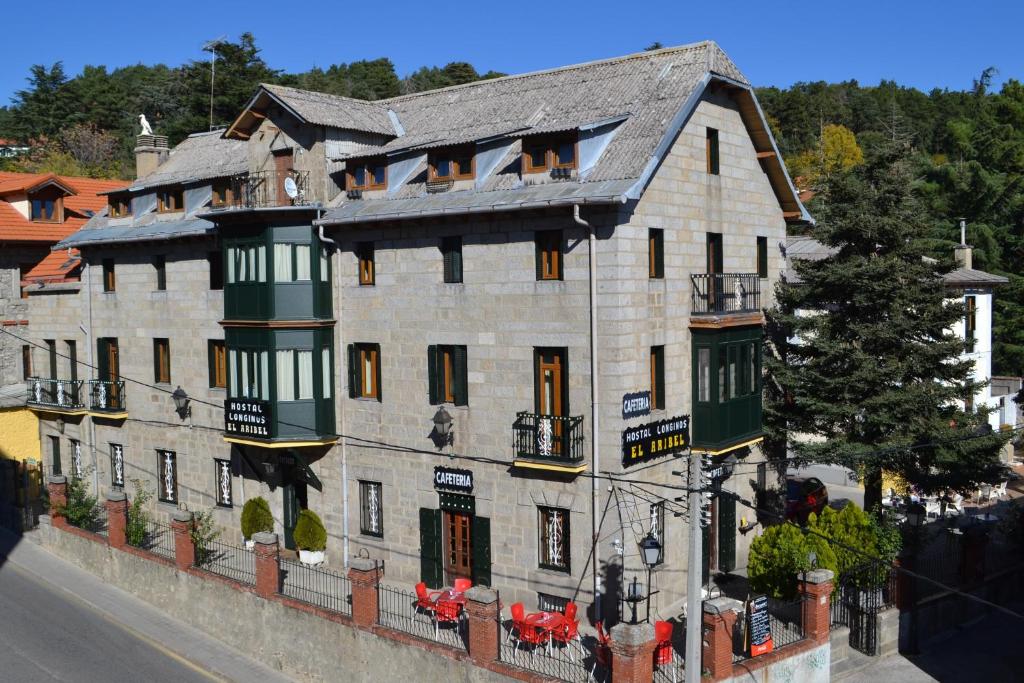 a large brick building with a clock on the side of it at Hostal Aribel Longinos in Cercedilla