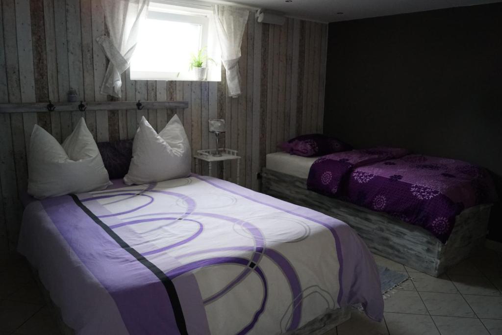 een slaapkamer met 2 bedden met paarse lakens en een raam bij Ferienwohnung Rehagen Süd in Mellensee
