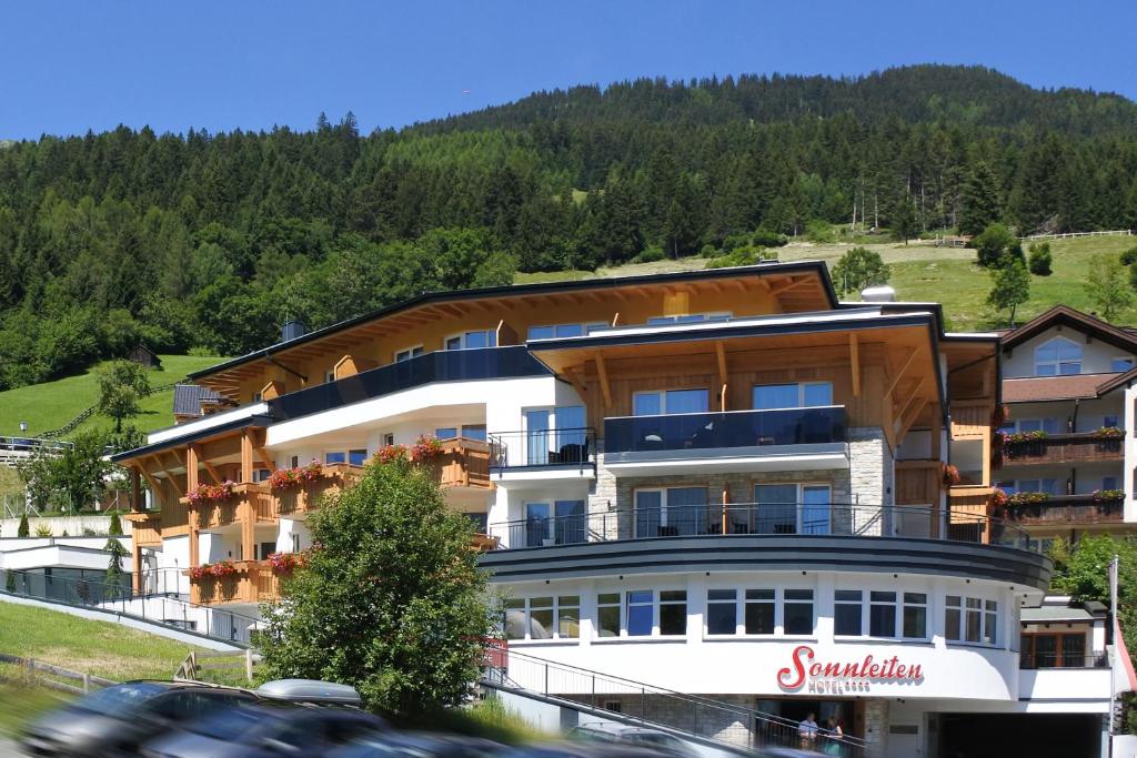 a large building on a hill with a mountain at Hotel Sonnleiten in Ladis
