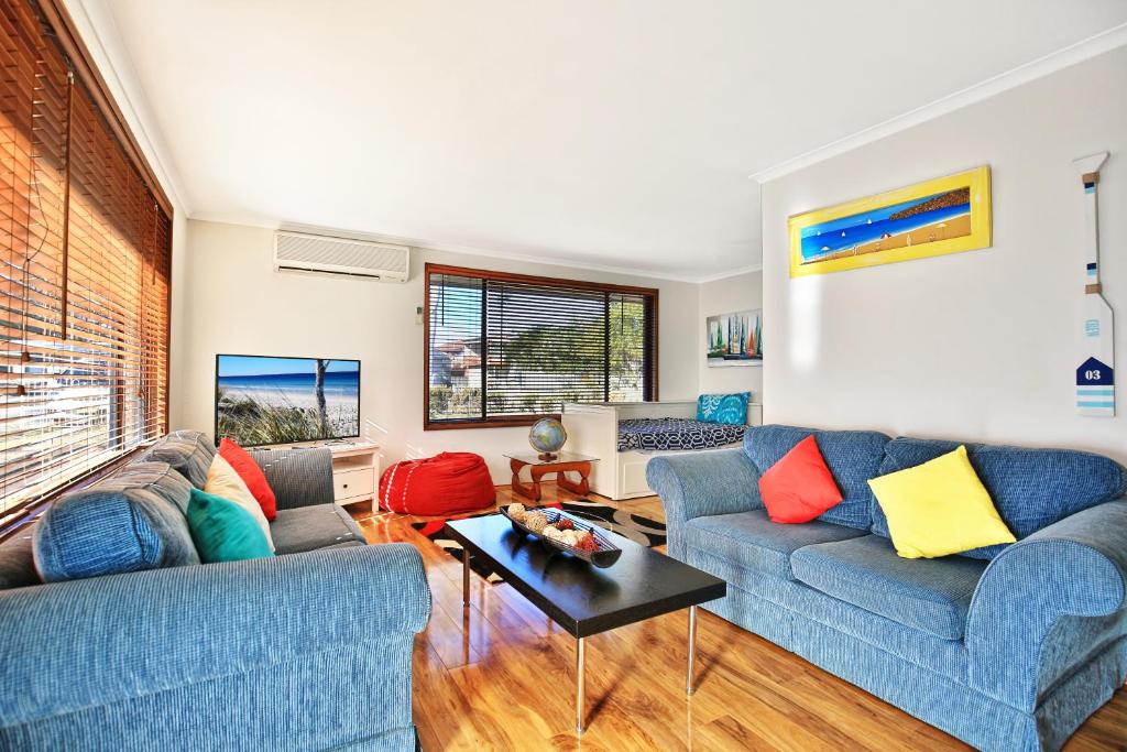 a living room with two blue couches and a table at Sandy Toes Beach House Jervis Bay - 2min to Beach in Callala Beach