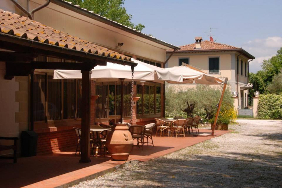 an outdoor patio with tables and chairs and umbrellas at Hotel Giuly in Torre del Lago Puccini