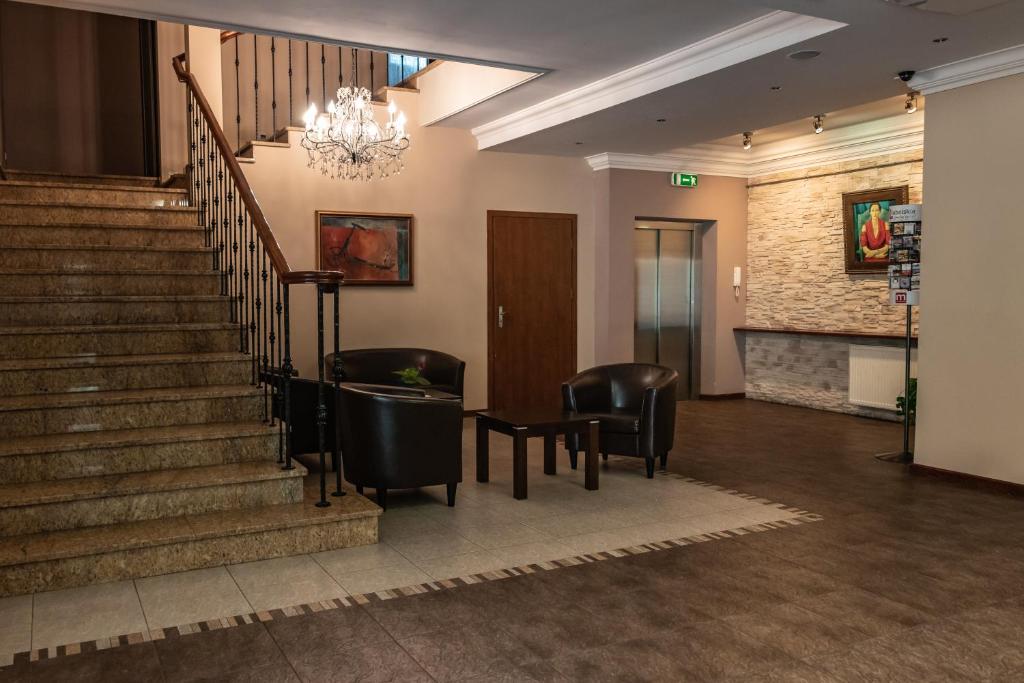 a lobby with stairs and chairs and a chandelier at Prima in Puławy