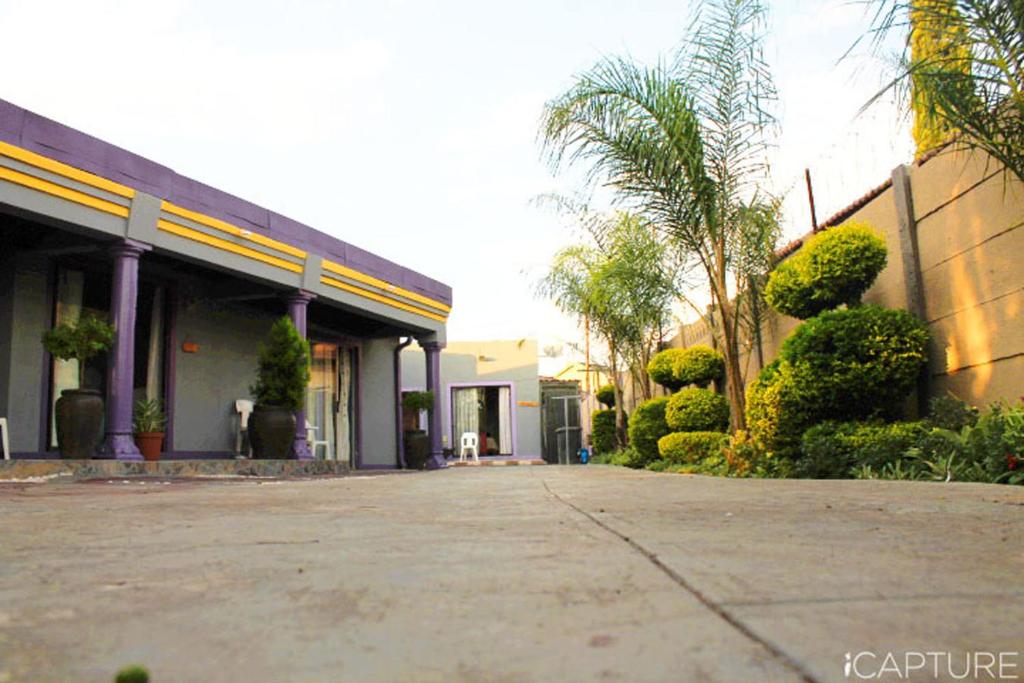 a building with palm trees and a driveway at Vicky B Bed and Breakfast in Mogwase