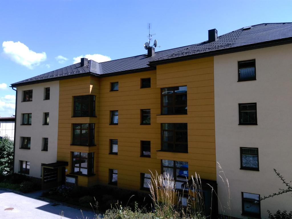 a yellow building with black windows at Apartmánek U lanovky in Janske Lazne