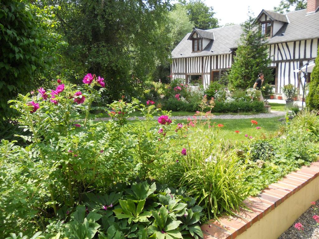 a garden in front of a house with flowers at Le Moulin des Roses in Neslette