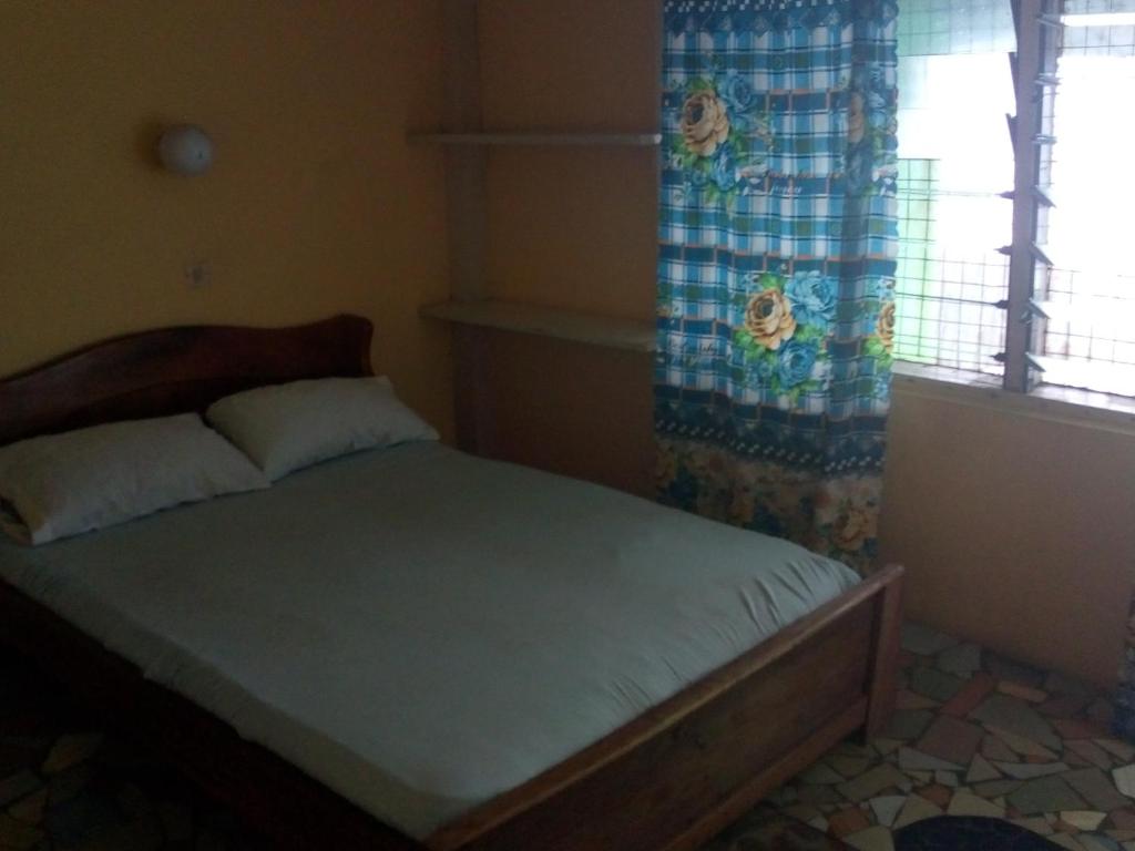 a small bedroom with a bed with a window at Rising Phoenix in Accra