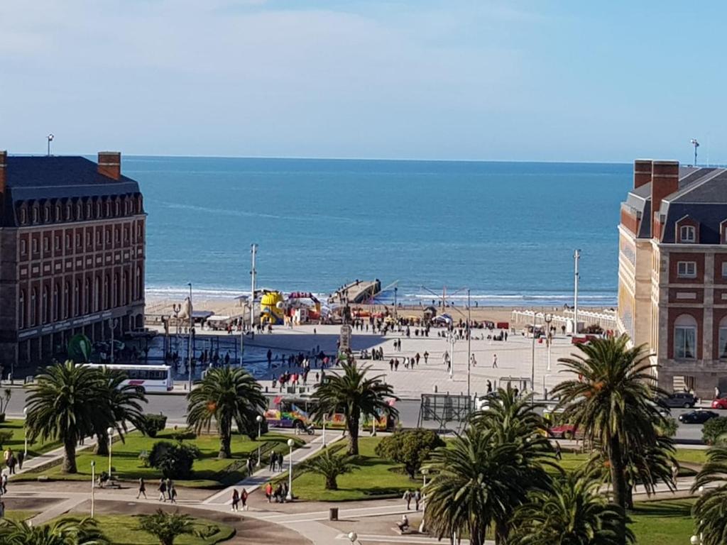 einen Strand mit Palmen und einem Gebäude und dem Meer in der Unterkunft Departamento Plaza Colón, Mar del Plata in Mar del Plata