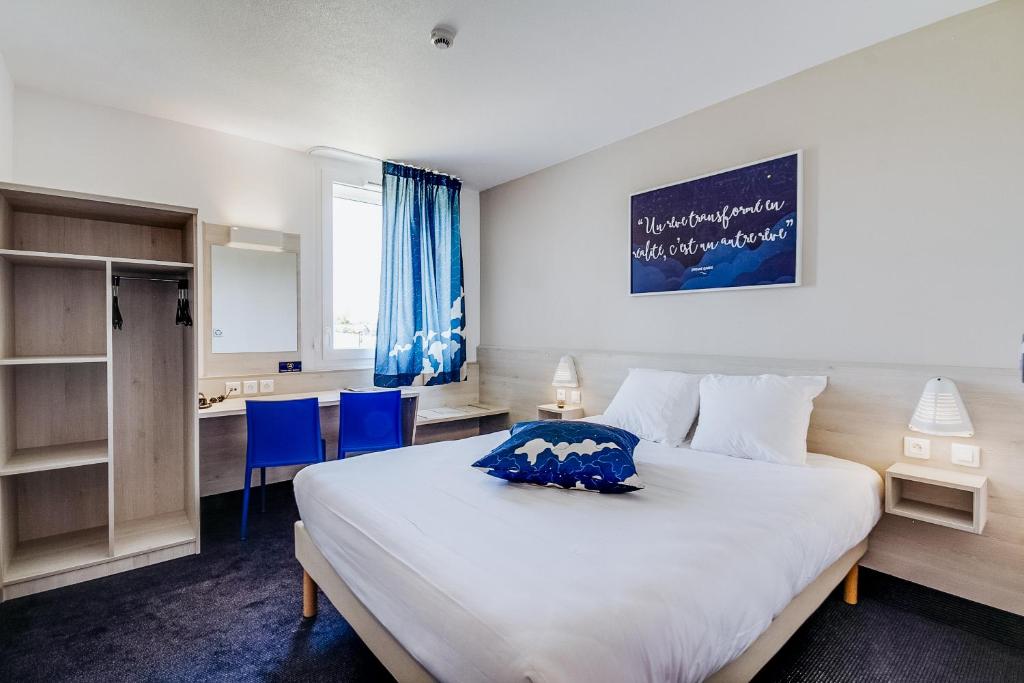 a bedroom with a large white bed and blue chairs at Ace Hôtel Le Mans in Saint-Saturnin