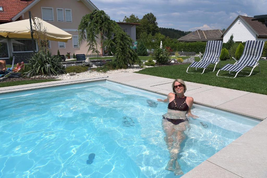 Una donna sta in piedi in una piscina di Ferienwohnungen Villa Vanessa a Gösselsdorf