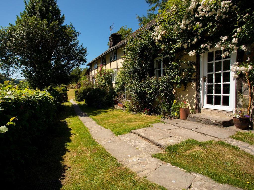 a house with a pathway leading to the front door at Dolgenau Cottages in Trefeglwys