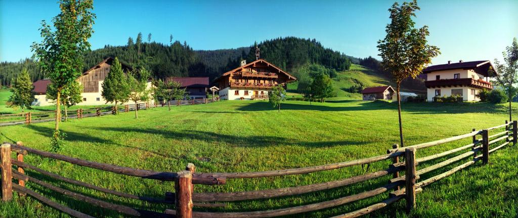 una valla de madera frente a un campo con casas en Steinbachgut, en Flachau