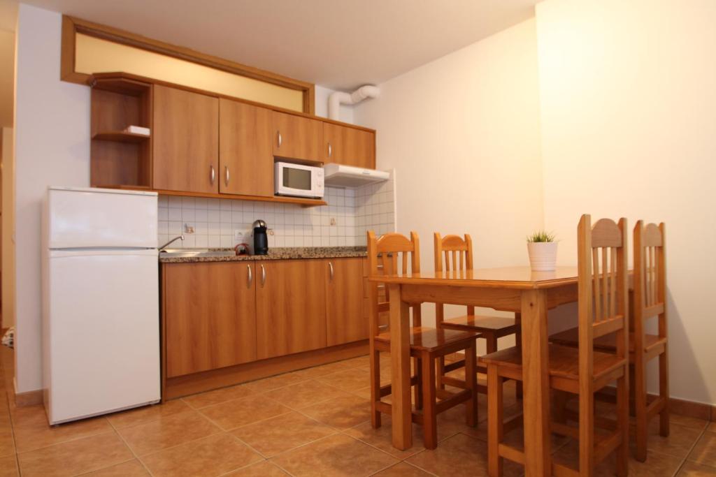 a kitchen with a table and a white refrigerator at Pont de Toneta 1,6 Ransol, Zona Grandvalira in Ransol