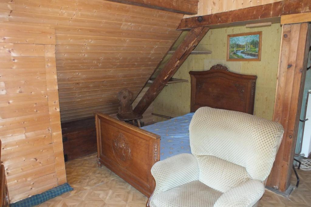 a bedroom with a bed and a chair in it at Gîte rustique sous combles in Merxheim