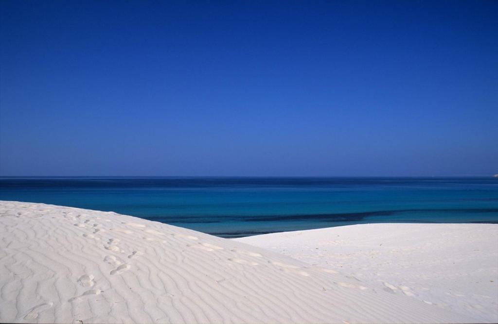 a white sand dune with the ocean in the background at B&B Sa Tuerra in Teulada