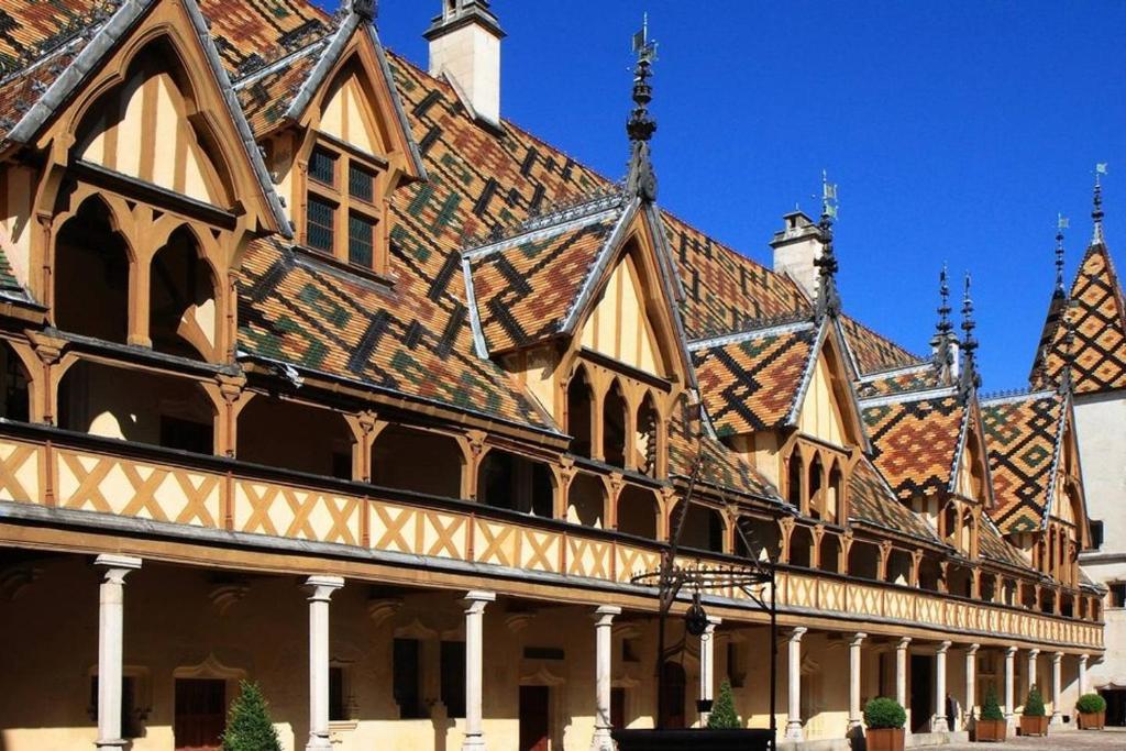 un grand bâtiment avec un toit carrelé dans l'établissement Le Bellecroix, à Beaune