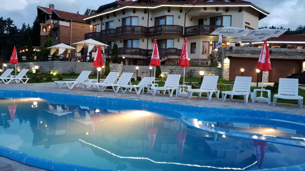 uma piscina com cadeiras e guarda-sóis em frente a um hotel em Family Hotel Eterno em Tsigov Chark