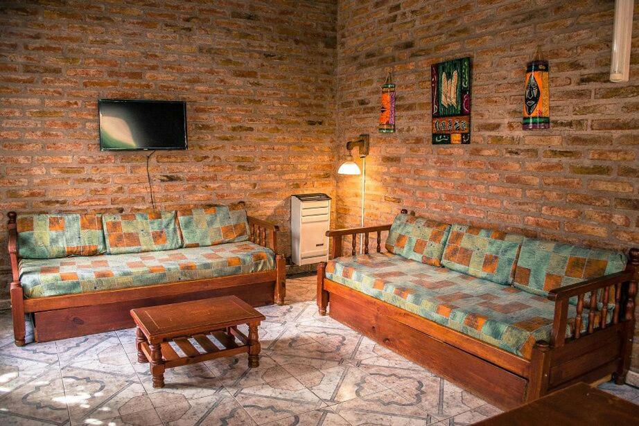 sala de estar con 2 sofás y TV en Cabañas Don Mario en Sierra de la Ventana
