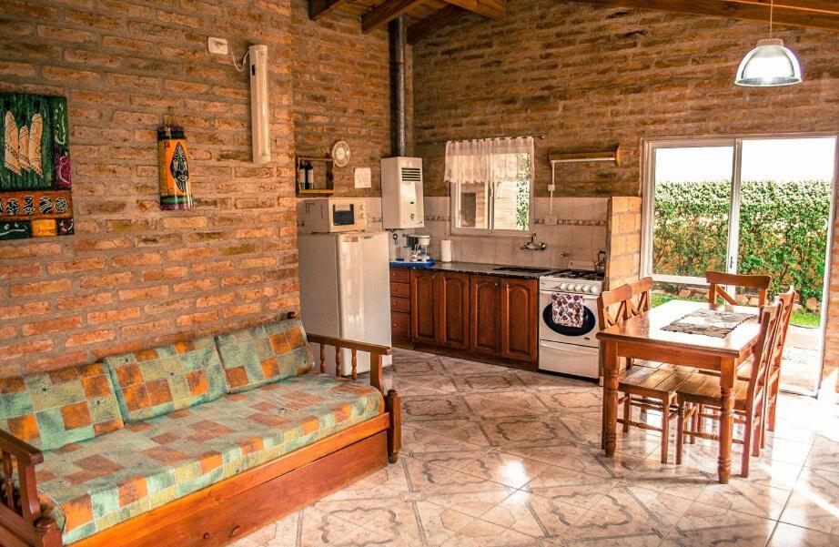 Una cocina con un sofá, una mesa y un refrigerador. en Cabañas Don Mario, en Sierra de la Ventana