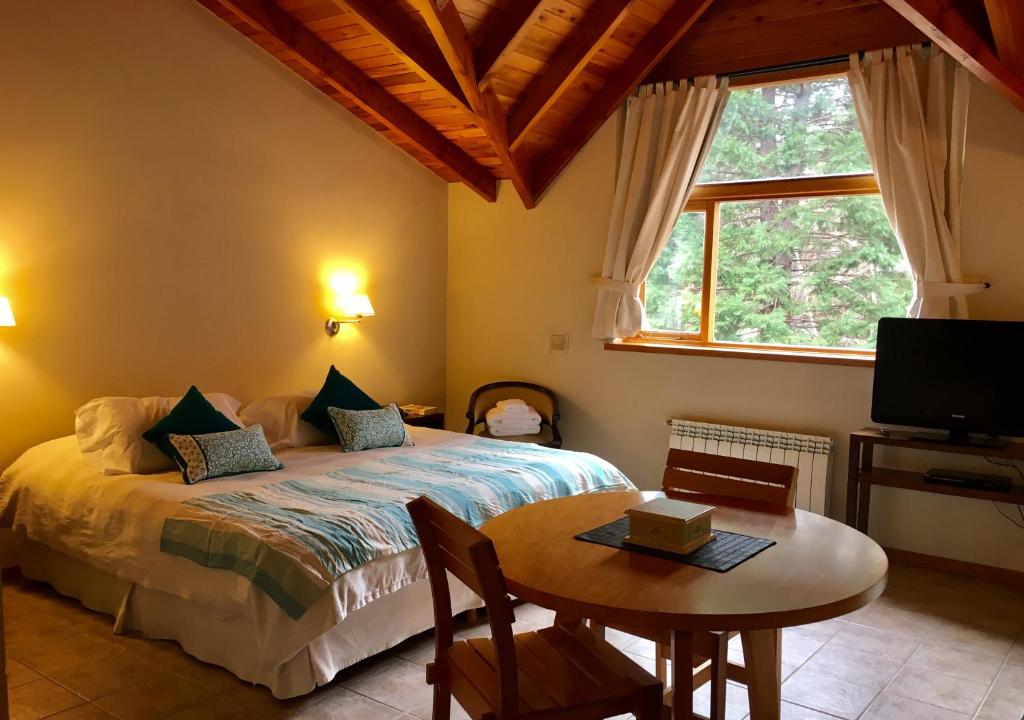 1 dormitorio con cama, mesa y ventana en Departamento con piscina en San Martín de los Andes