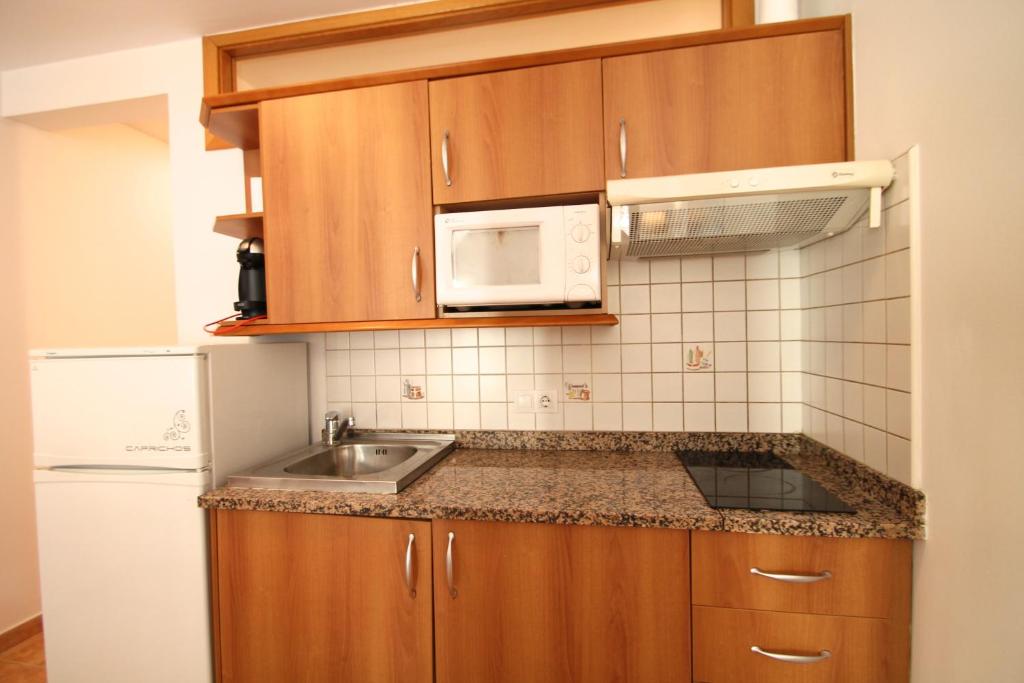eine Küche mit Holzschränken, einer Spüle und einer Mikrowelle in der Unterkunft Pont de Toneta 3,2 Ransol, Zona Grandvalira in Ransol