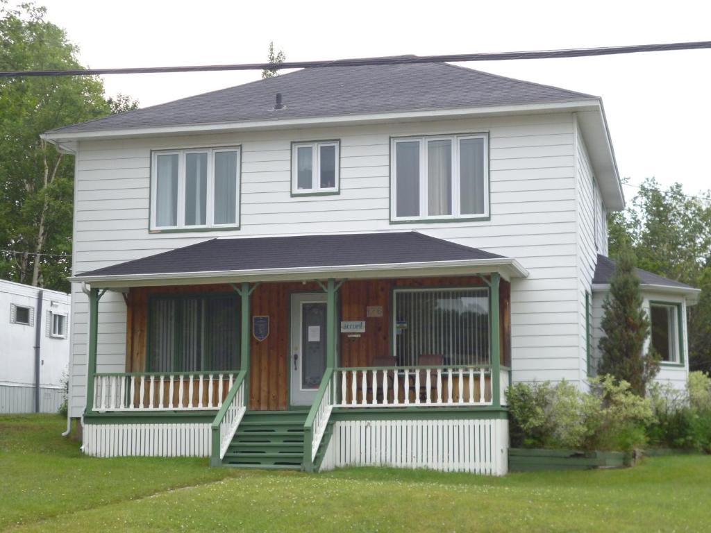 a white house with a porch and a front door at Hébergement Maison Fortier in Tadoussac