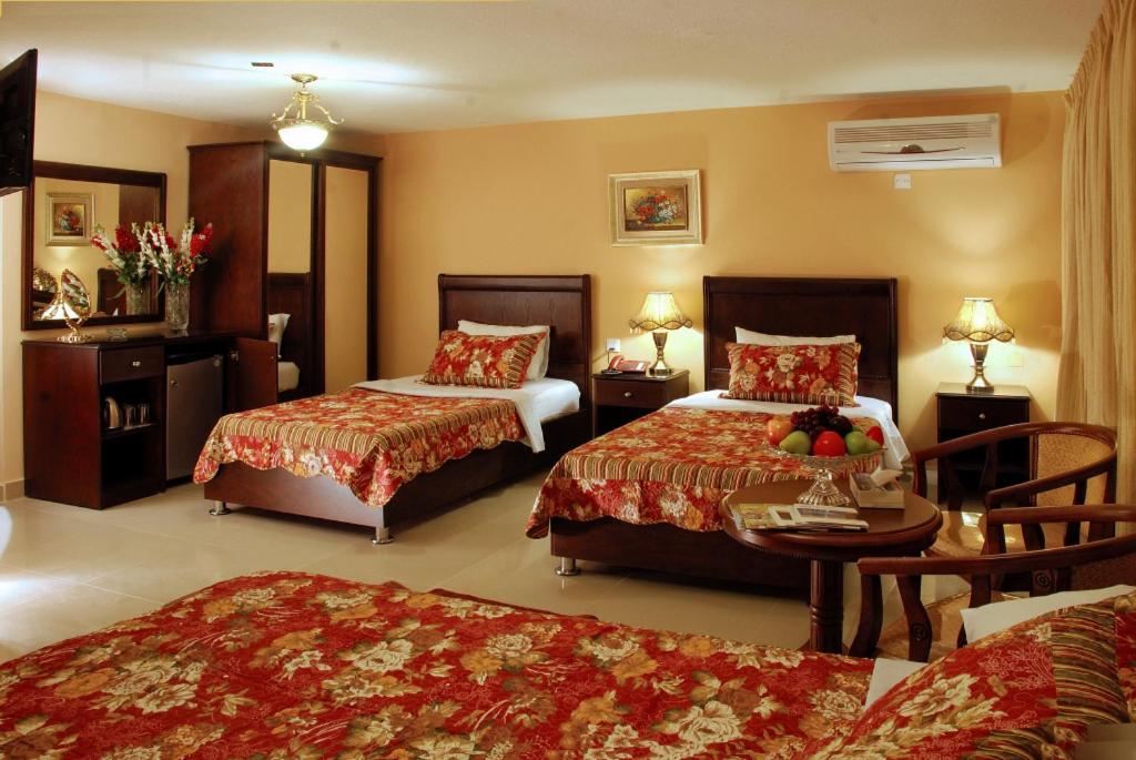 a hotel room with two beds and a table at Jardaneh Hotel in Aqaba