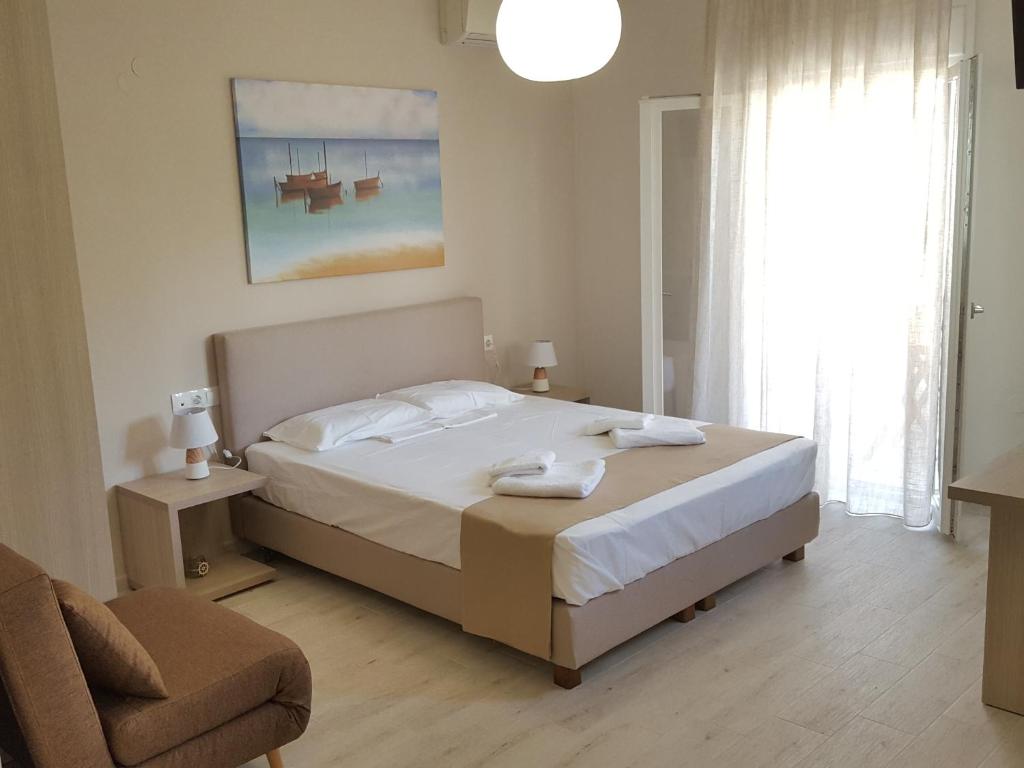 a bedroom with a bed and a chair and a window at Minimalistic Studio Apartments in Heraklio Town