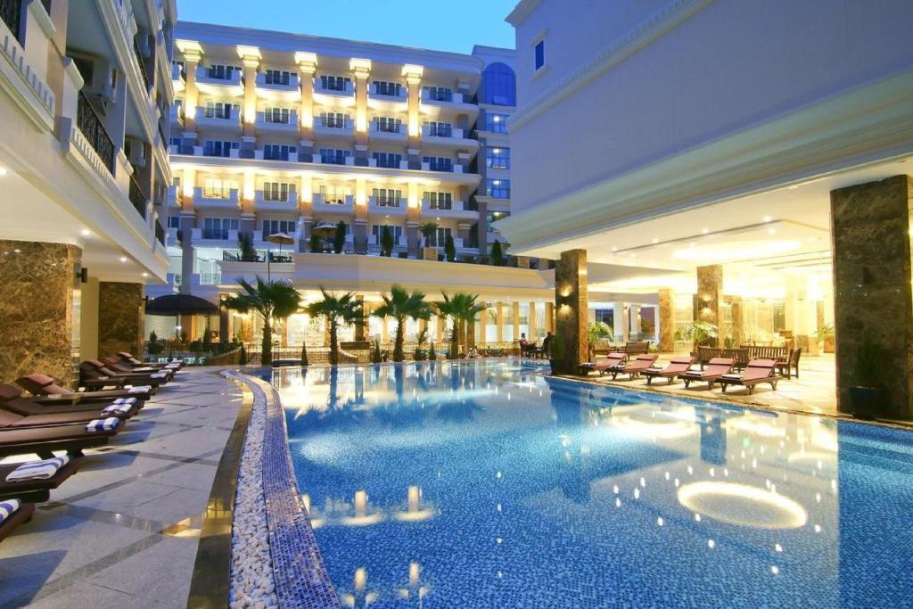 a hotel with a swimming pool in front of a building at LK Miracle Suite - SHA Extra Plus in Pattaya South