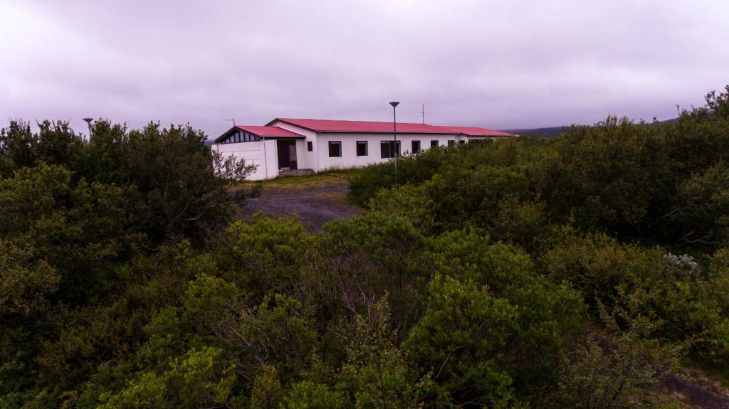 un bâtiment blanc avec un toit rouge au sommet d'une colline dans l'établissement Dettifoss Guesthouse, à Skinnastadur