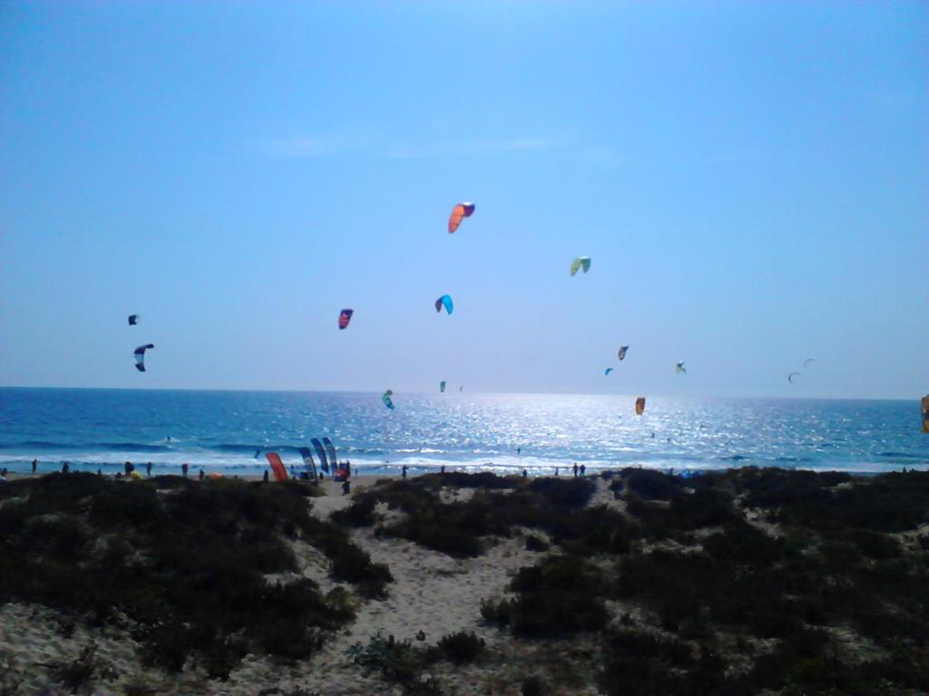 a group of people flying kites on the beach at Oceanos in Costa da Caparica