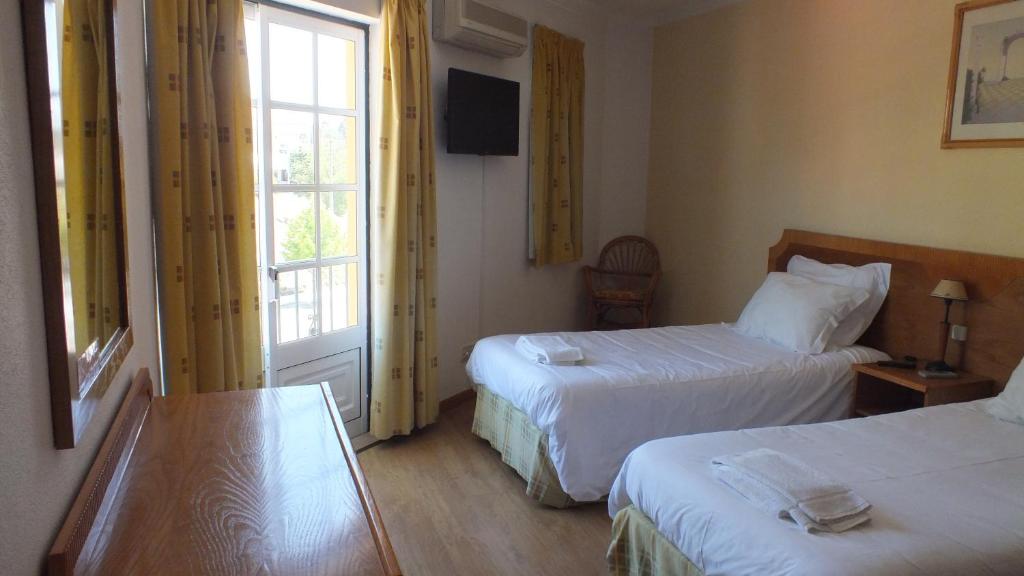 a hotel room with two beds and a window at Residencial Gil Vicente in Sardoal
