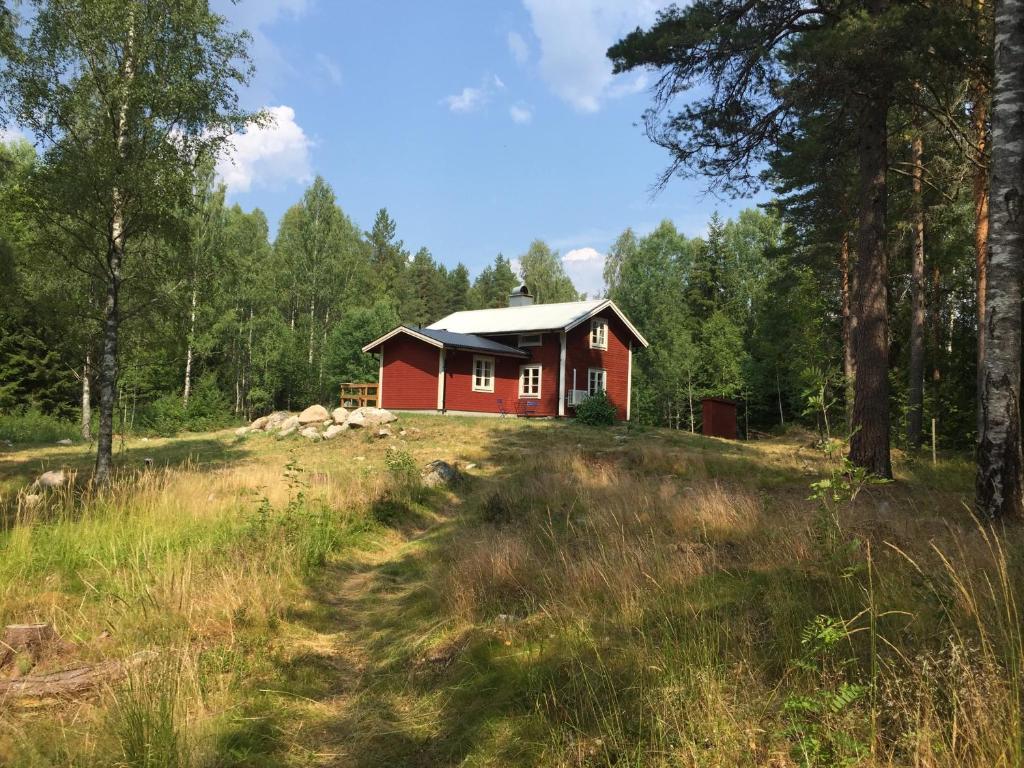 una casa roja en la cima de una colina en el bosque en Hyttsnåret, en Östra Löa