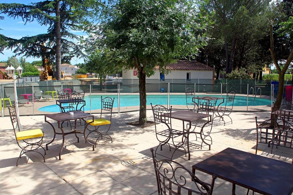 吉尼亞克的住宿－Logis Hotel Le Vieux Moulin，一组桌子和椅子,位于游泳池前