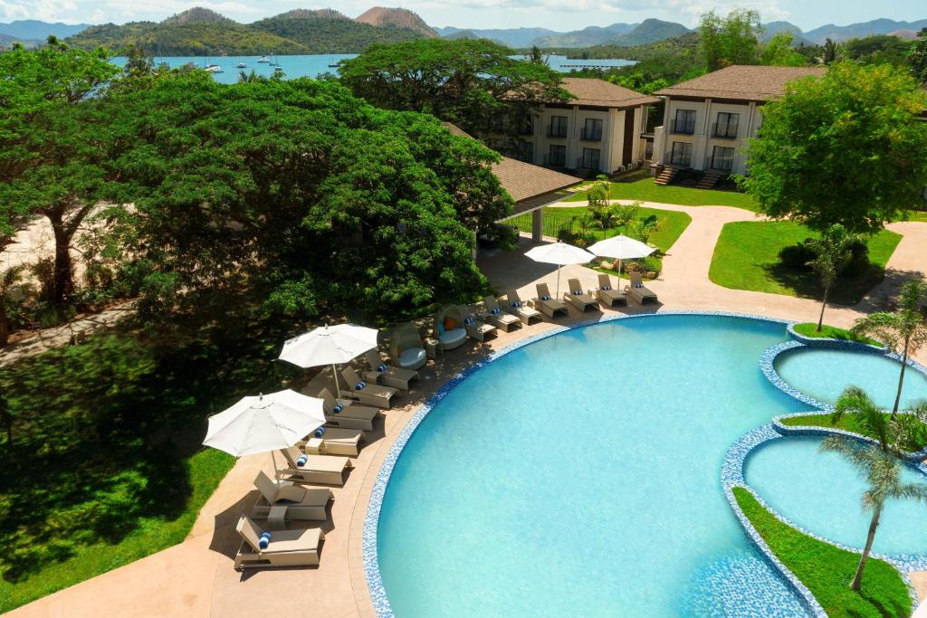 uma vista superior para uma piscina com cadeiras e guarda-sóis em Bacau Bay Resort Coron em Coron