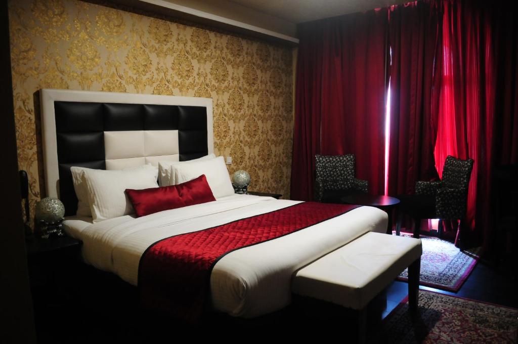 a bedroom with a large bed and red curtains at Hotel Rose Petal Srinagar in Srinagar