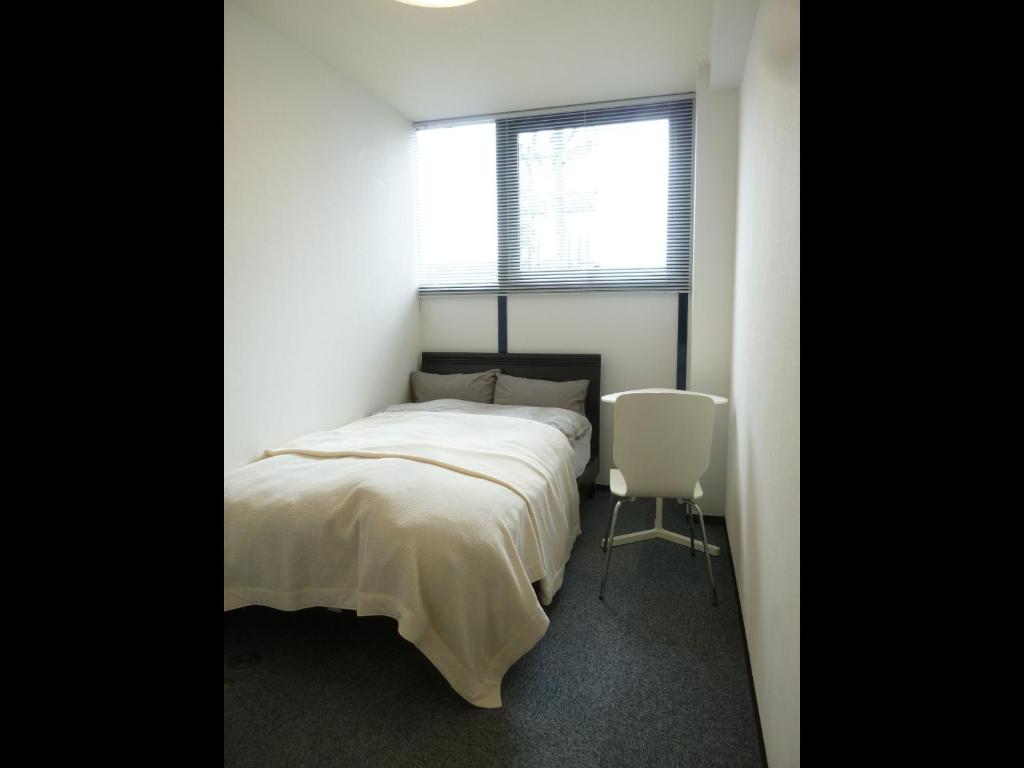 ein Schlafzimmer mit einem weißen Bett und einem Fenster in der Unterkunft Nagoya Motoyama House B in Nagoya