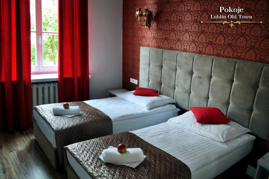 two beds in a hotel room with red curtains at Lublin Old Town Rooms in Lublin