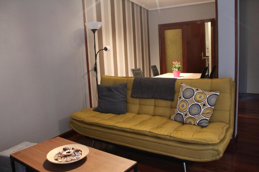 a living room with a yellow couch and a table at Bilbao center apartamento 2 hab Parking Privado in Bilbao