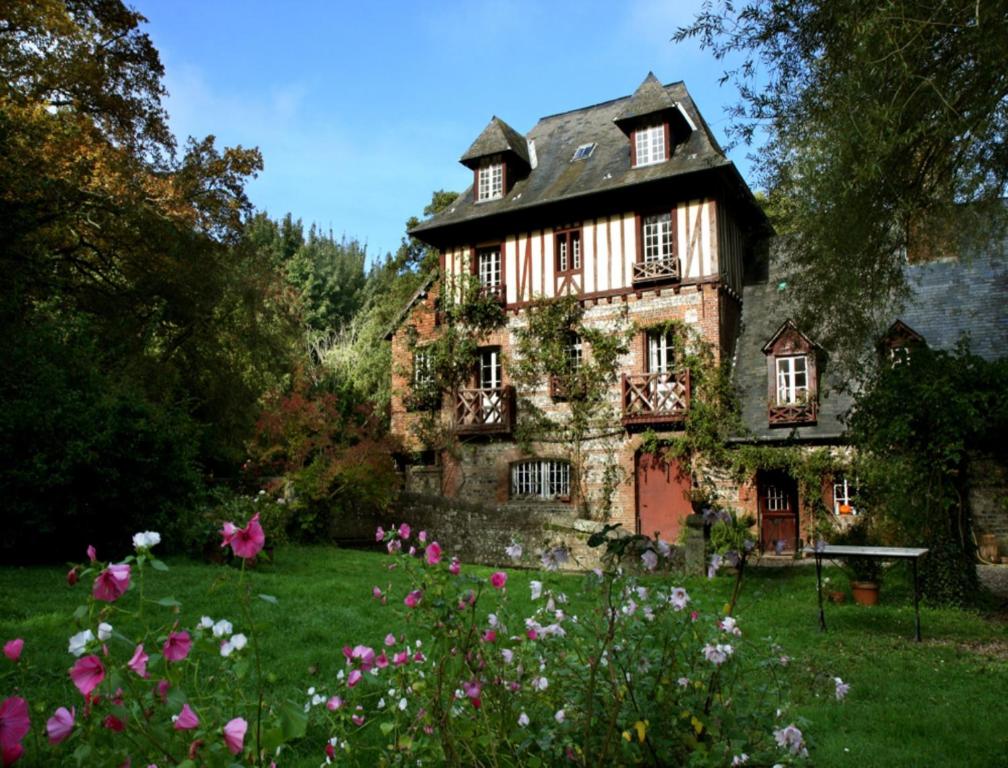 une vieille maison avec des fleurs devant elle dans l'établissement Le Moulin Fleuri du Petit Appeville, à Petit-Appeville