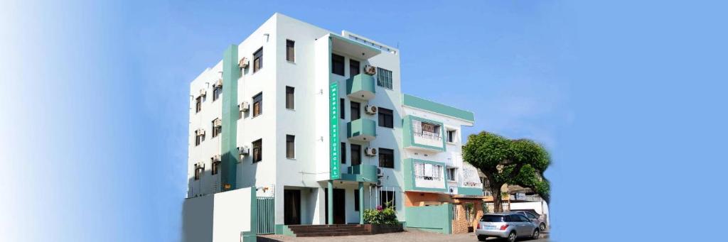 a white and green building with a car parked next to it at Pensao Marhaba Residencial in Maputo