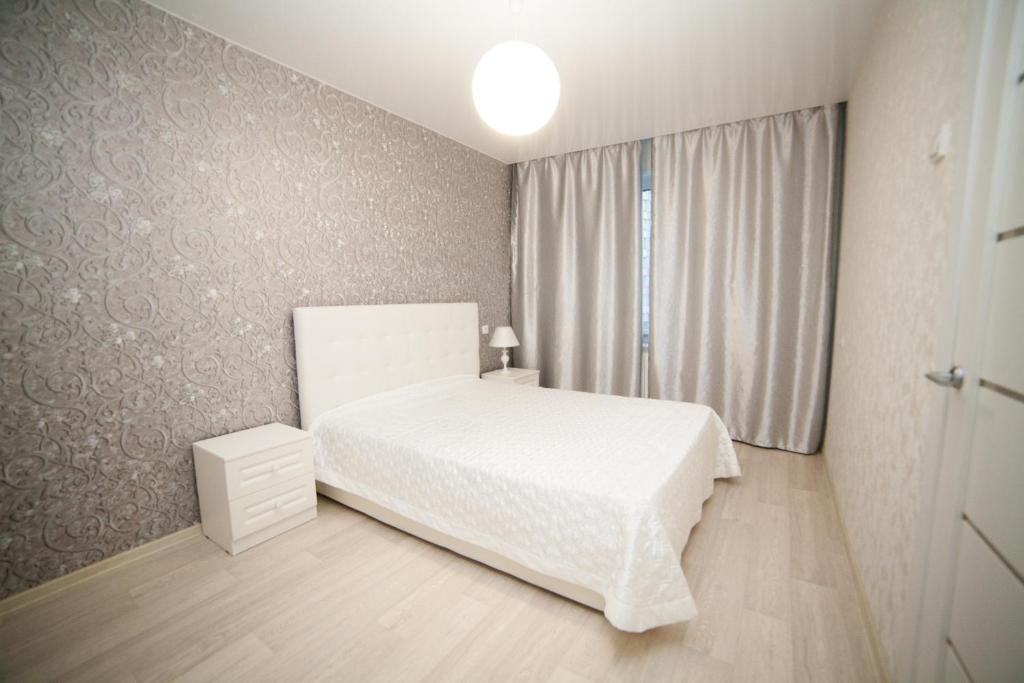 een slaapkamer met een wit bed en een raam bij Alekseyeva Apartament in Krasnojarsk