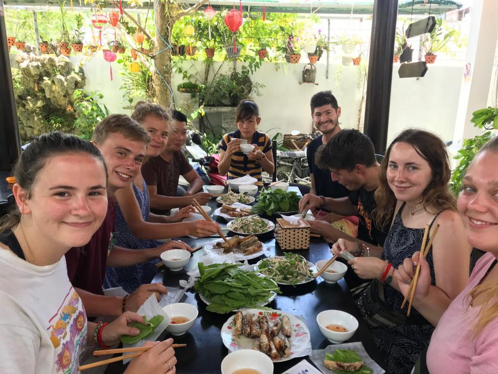 a group of people sitting around a table eating food at Cheerful Hoi An Hostel in Hoi An