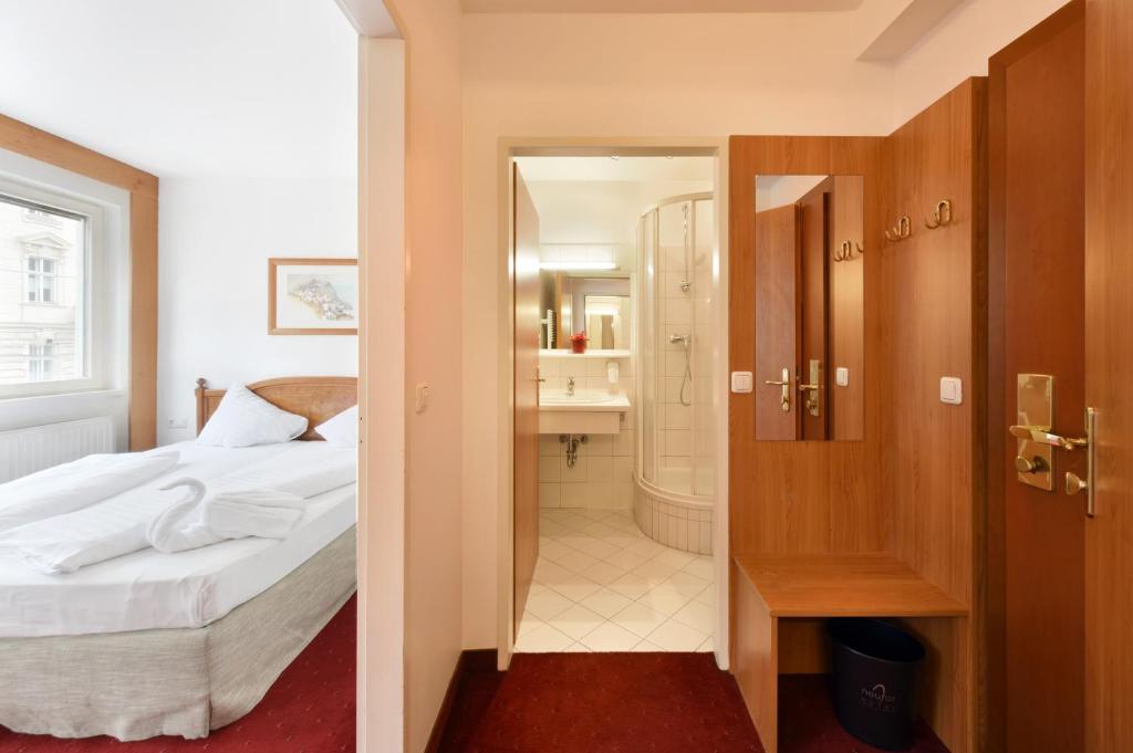 a bedroom with a bed and a walk in shower at Am Neutor Hotel Salzburg Zentrum in Salzburg