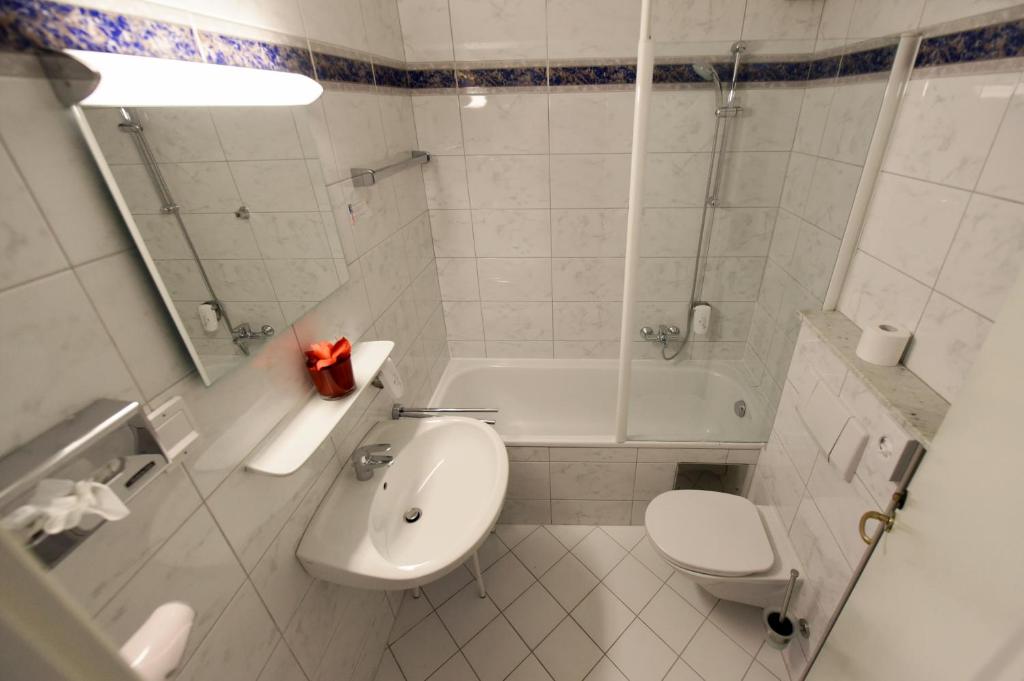 a bathroom with a toilet and a sink and a tub at Am Neutor Hotel Salzburg Zentrum in Salzburg
